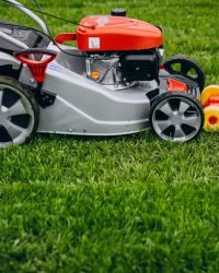 man cutting grass with lawn mover in the back yard