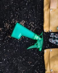 Fertilizing spray bottle near bag with gardening tools